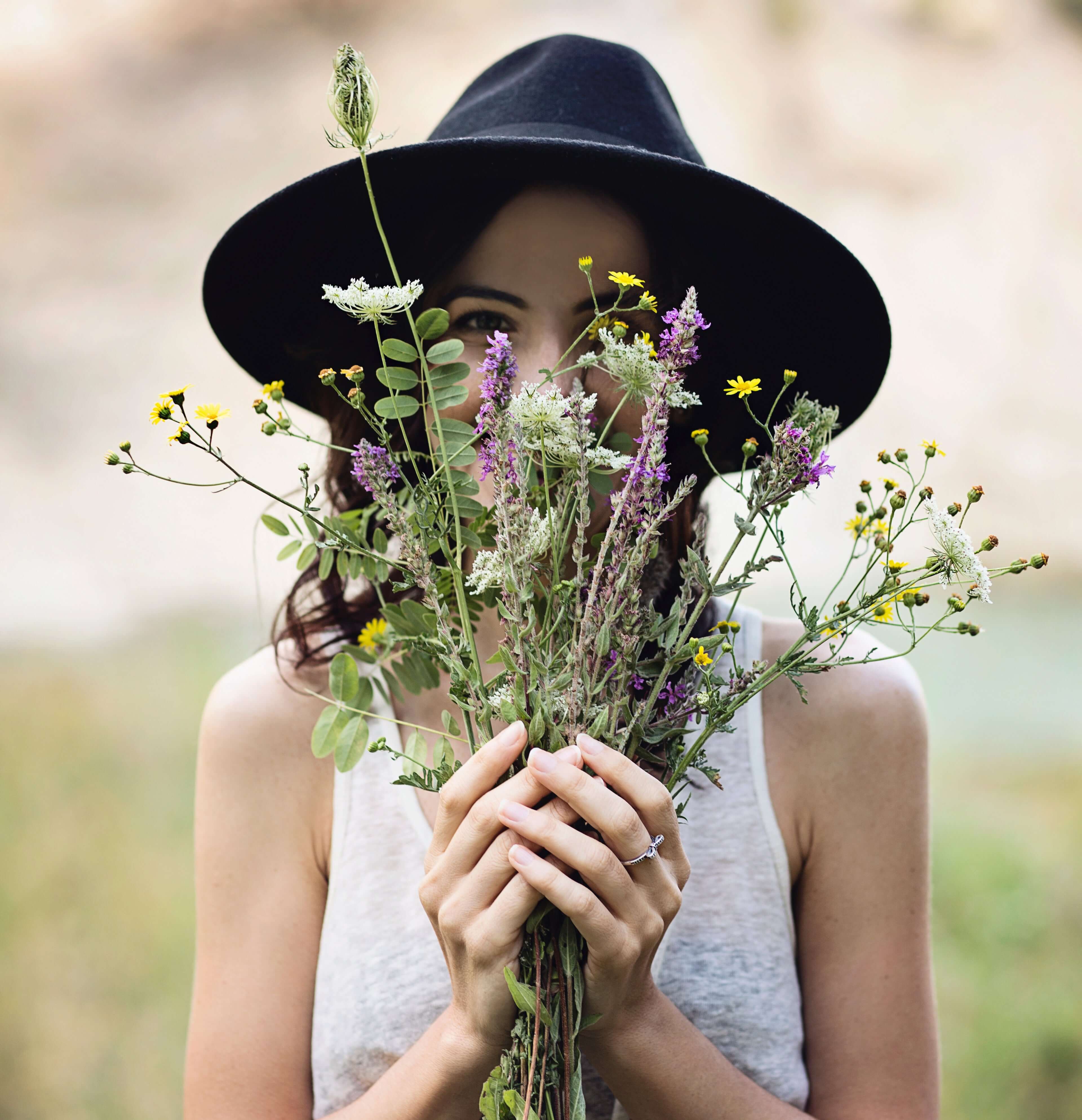 Smiling woman holding wild flowers and herbs